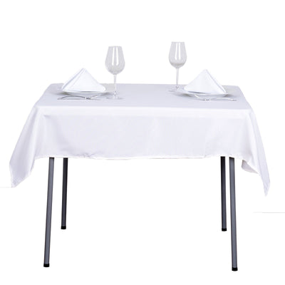 Elegant dining table set with glasses and napkins on a white tablecloth.