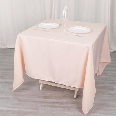Peach tablecloth draped over a table with plates and glassware
