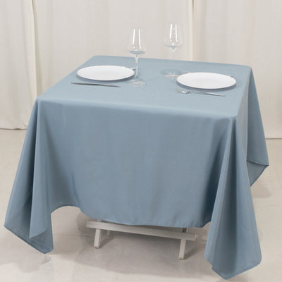 Blue tablecloth on a dining table set with plates and glasses.
