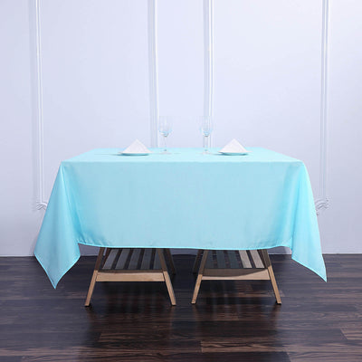 Light blue tablecloth on a wooden table with glassware and napkins.