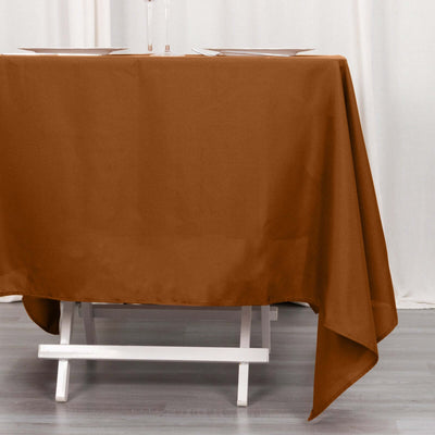 Brown tablecloth draped over a white table with plates on top.