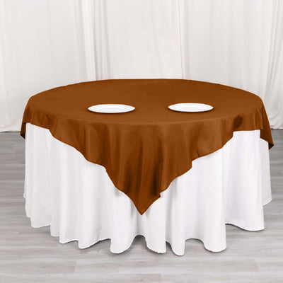 Brown tablecloth draped over a round table with white plates.