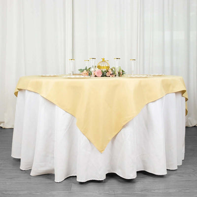 Elegant round table with gold tablecloth and floral centerpiece on a white backdrop.