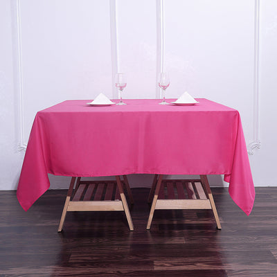 Pink tablecloth draped over a wooden table with glasses and napkins.