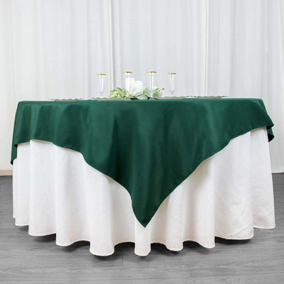 Green tablecloth draped over a round table with a white skirt.