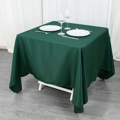 Green tablecloth draped over a dining table set with plates and glasses.