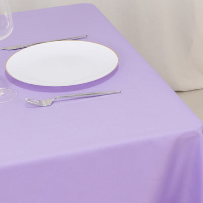 Purple tablecloth with a white plate and cutlery on a dining table setting.