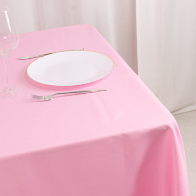 Pink tablecloth with a white plate and silver utensils set on a table.