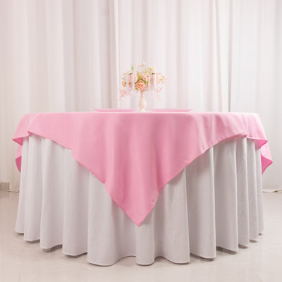 Pink tablecloth draped over a round table with a floral centerpiece.