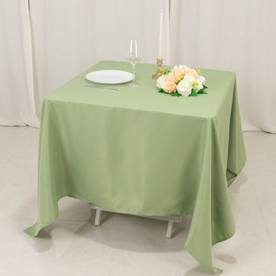 Green tablecloth draped over a table set with a plate, glass, and floral centerpiece.