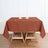 Rust-colored tablecloth on a wooden table with candle holders