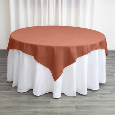 Round table with a rust-colored tablecloth on a white table skirt.