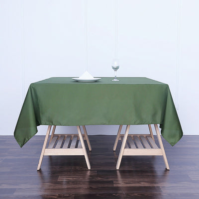 Green tablecloth draped on a wooden table with a glass and napkin.