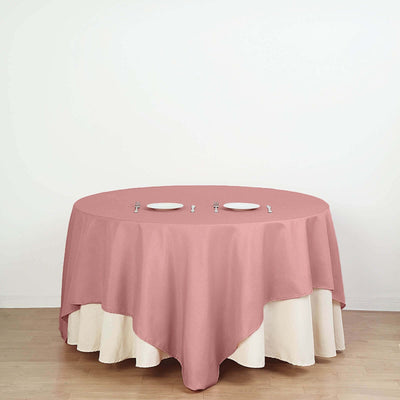 Round table with a pink tablecloth and three plates on a white background.