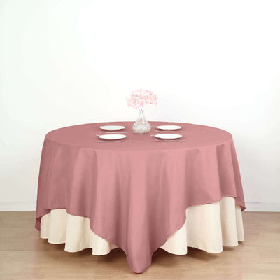 Round table with a pink and cream tablecloth, set for dining.