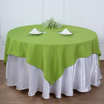 Round green tablecloth on a dining table with silver skirt and elegant table setting.