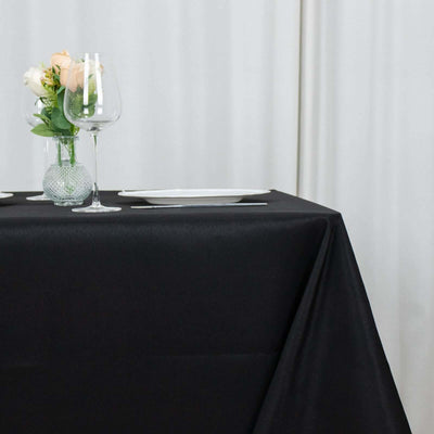 Elegant black table setting with glassware and floral centerpiece.