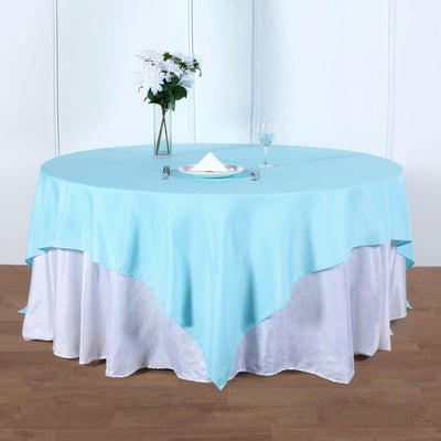 Round blue tablecloth draped over a white table with floral centerpiece.