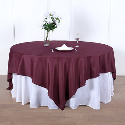 Round burgundy tablecloth draped elegantly over a white tablecloth.