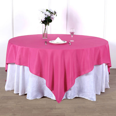 Pink round tablecloth draped over a white table with flowers and glassware.