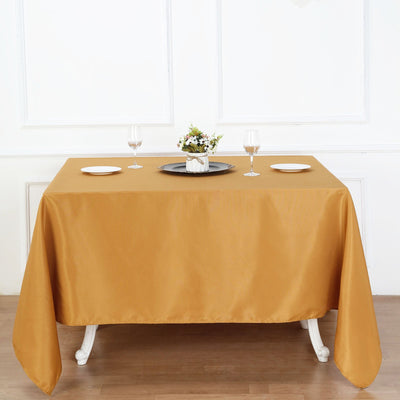 Gold tablecloth draped on a dining table with plates and glasses.