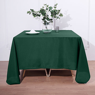 Green tablecloth draped over a table with floral centerpiece and tableware.