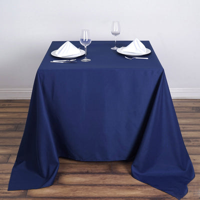 Elegant navy tablecloth with dinnerware and glassware set for a dining experience.