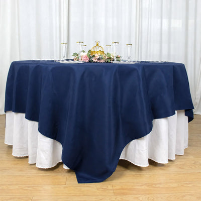 Navy blue round tablecloth with white underlay and floral centerpiece centerpiece