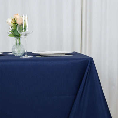 Elegant table setting with navy tablecloth, wine glass, plate, and floral vase