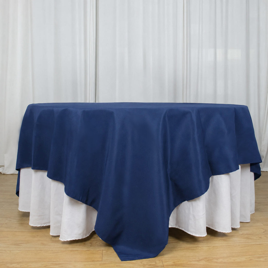 Round table with navy blue overlay and white floor-length tablecloth