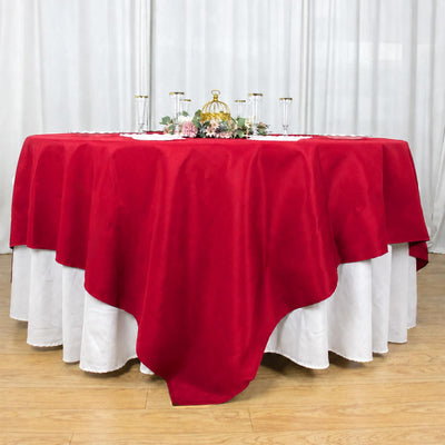 Red round tablecloth with white underlay and elegant centerpiece display