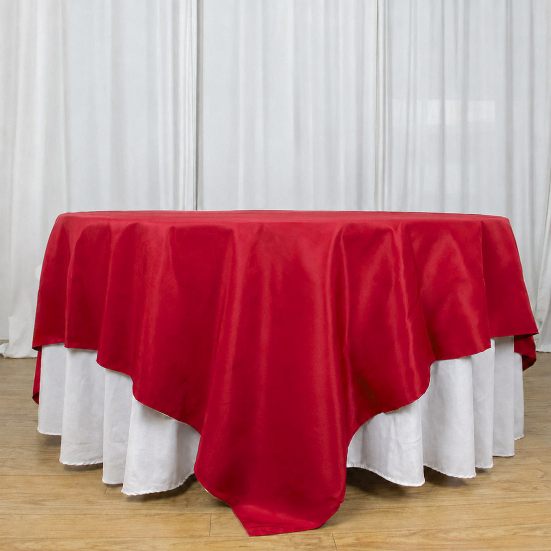 Red round tablecloth with white underlay on banquet table