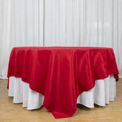 Red round tablecloth with white underlay on banquet table