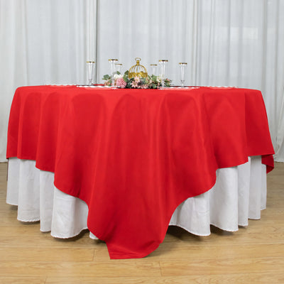 Red tablecloth with white underlay and floral centerpiece on a round table