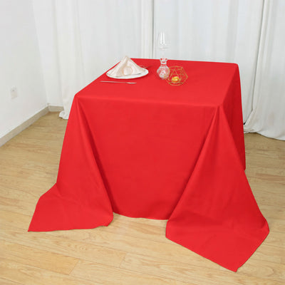 Red tablecloth dining table with elegant decorative place setting and glassware