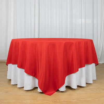 Red sheer round tablecloth over white table skirt in elegant event setup