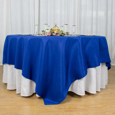Elegant blue round tablecloth with white underlay and floral centerpiece