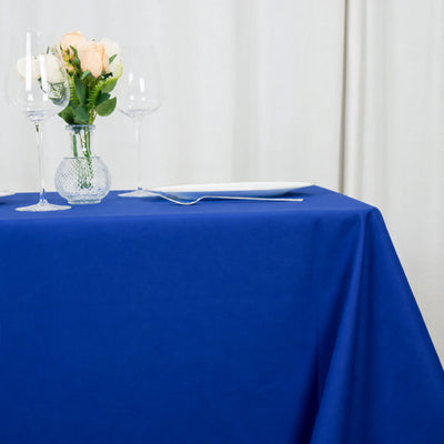 Blue tablecloth with wine glasses, rose bouquet, and white dinner plate