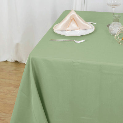 Green tablecloth with elegant napkin and decorative plate set on a dining table.