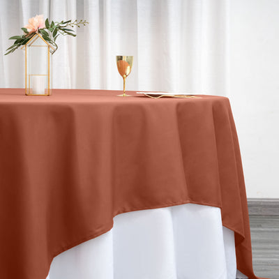 Rust orange tablecloth draped elegantly over a white table with floral decor.
