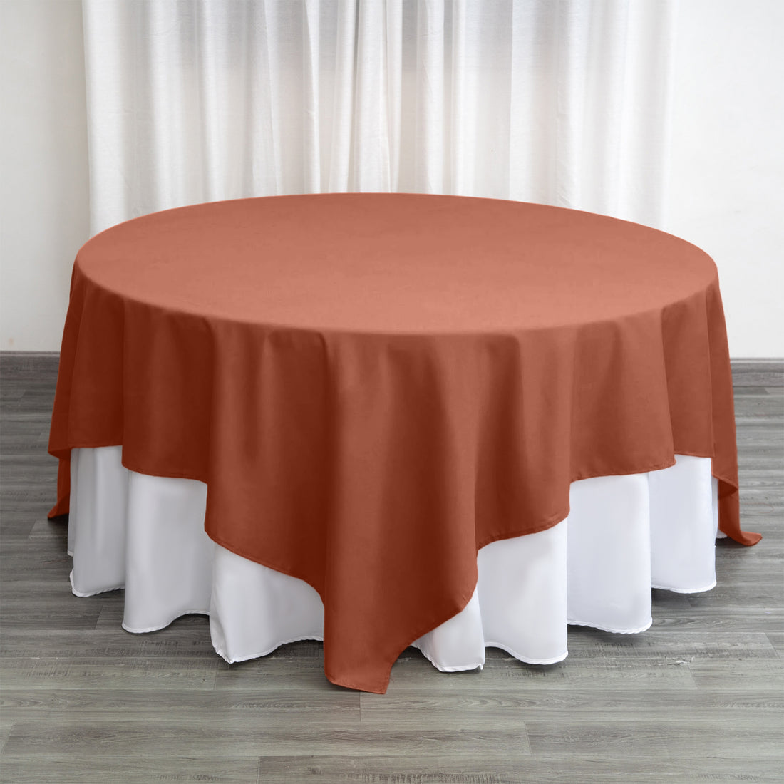Round rust-colored tablecloth draped over a white table.