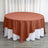 Round rust-colored tablecloth draped over a white table.