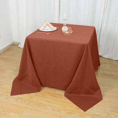 Brown tablecloth draped over a wooden table with a glass and decor.