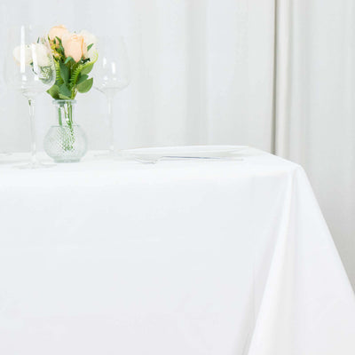 Elegant table setting with flowers and glassware on a white tablecloth.