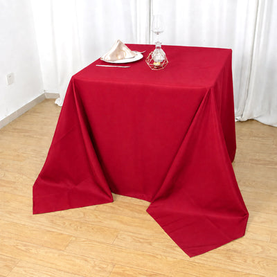 Red tablecloth set on a dining table with elegant place settings and candle holder