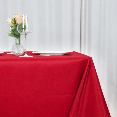 Elegant red tablecloth with flowers, wine glass, and white plate setting