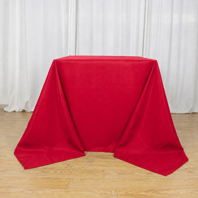 Red tablecloth draped over a rectangular table in a white studio backdrop