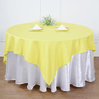 Yellow round tablecloth draped over a silver tablecloth for elegant dining.