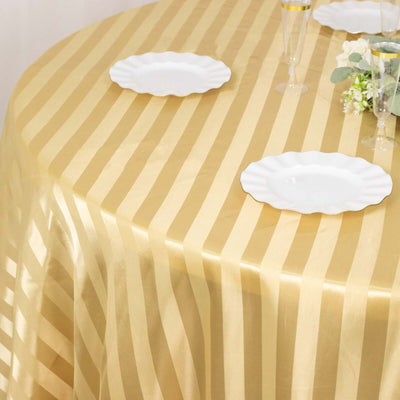 Gold striped tablecloth draped over a round table with white plates and decorations.