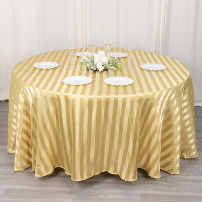 Gold striped round tablecloth on a dining table with white plates and floral centerpiece.
